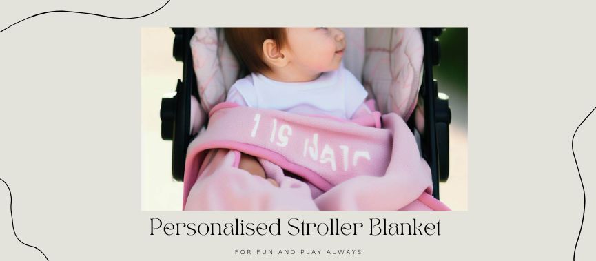 a picture of 1 year old baby girl in the stroller witha personalized stroller blanket wrapped around the stroller